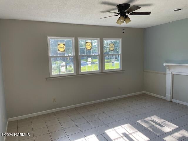 tiled empty room with a textured ceiling and ceiling fan