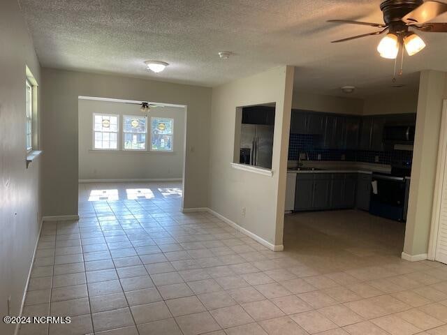 kitchen with light tile patterned flooring, sink, range, ceiling fan, and stainless steel fridge with ice dispenser