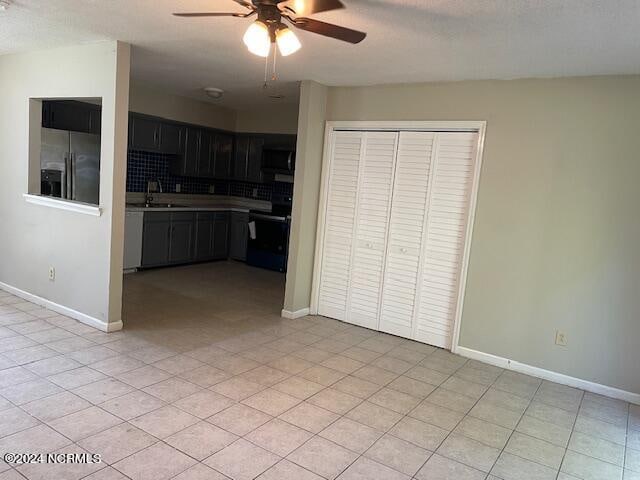 kitchen featuring sink, range, a textured ceiling, stainless steel fridge, and ceiling fan