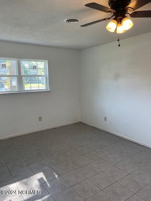 tiled spare room featuring ceiling fan and a textured ceiling