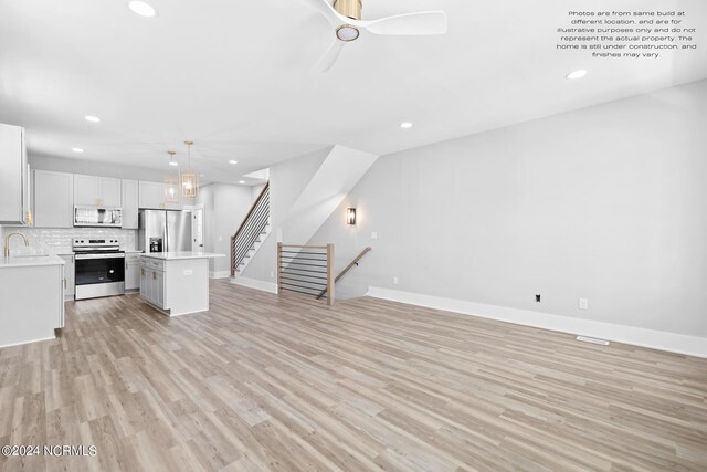 unfurnished living room featuring ceiling fan, sink, and light wood-type flooring