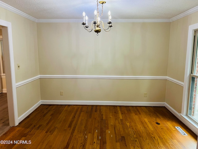 unfurnished room with a notable chandelier, a textured ceiling, hardwood / wood-style floors, and crown molding