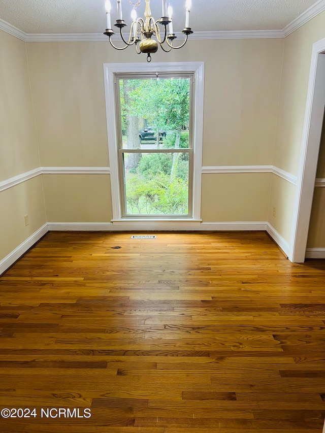 unfurnished dining area with hardwood / wood-style flooring, crown molding, a notable chandelier, and a textured ceiling