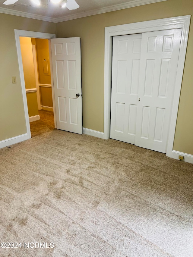 unfurnished bedroom with carpet, a closet, ceiling fan, and crown molding