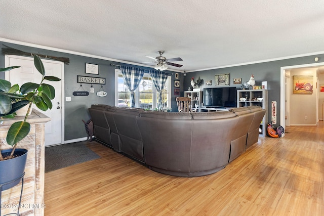 living room featuring hardwood / wood-style flooring, ceiling fan, ornamental molding, and a textured ceiling