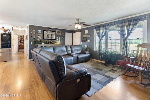 living room with ceiling fan, light hardwood / wood-style floors, a textured ceiling, and ornamental molding