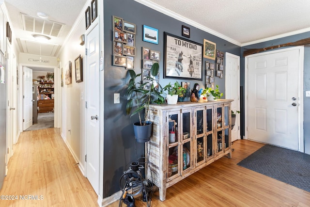 entrance foyer with wood-type flooring, a textured ceiling, and ornamental molding