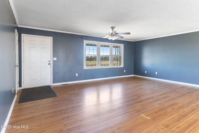 interior space featuring a textured ceiling, ornamental molding, wood finished floors, and baseboards