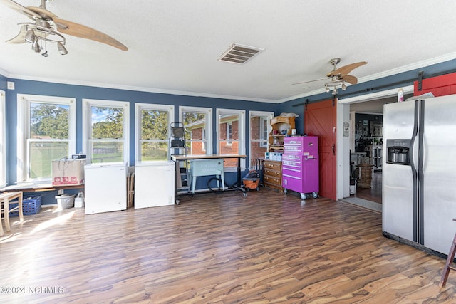 interior space featuring crown molding, dark hardwood / wood-style floors, stainless steel fridge, a barn door, and a textured ceiling