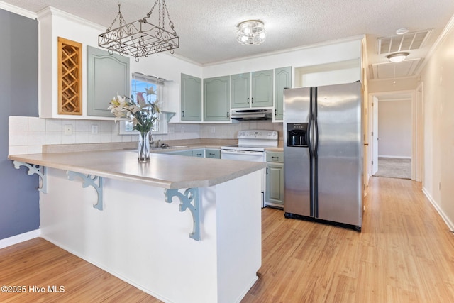 kitchen with stainless steel fridge, visible vents, a kitchen breakfast bar, a peninsula, and under cabinet range hood