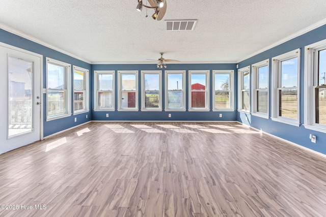 unfurnished sunroom featuring visible vents and a ceiling fan