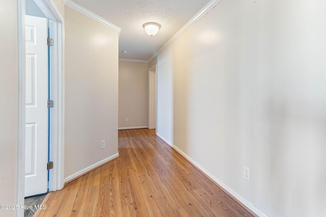 hall with light wood-style floors, crown molding, baseboards, and a textured ceiling