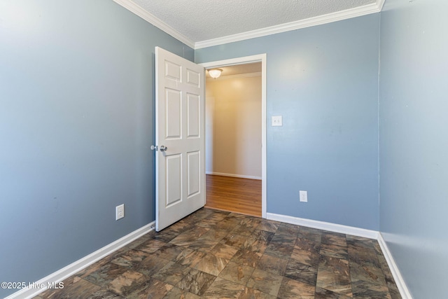 empty room featuring stone finish floor, baseboards, ornamental molding, and a textured ceiling