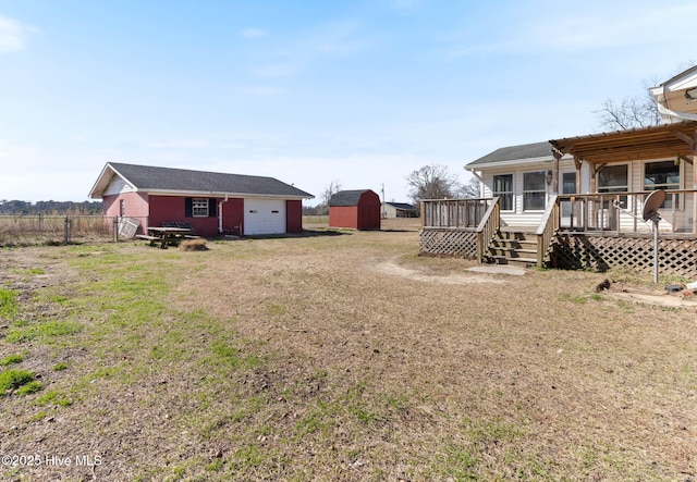 view of yard featuring an outbuilding, a shed, a deck, and fence