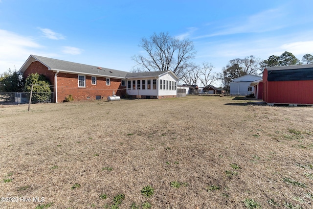 back of property featuring a yard, fence, a sunroom, and brick siding