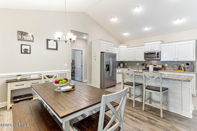 dining space featuring ceiling fan with notable chandelier, vaulted ceiling, and hardwood / wood-style floors