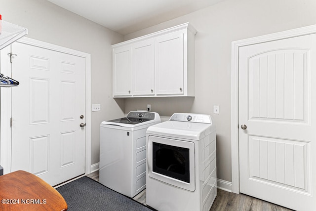 laundry room with washing machine and clothes dryer, cabinets, and dark hardwood / wood-style flooring