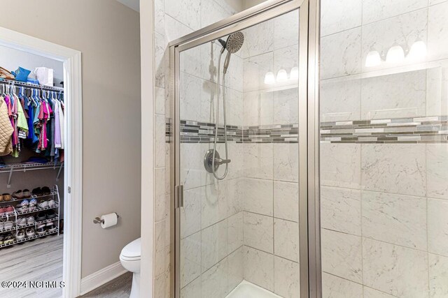 bathroom featuring hardwood / wood-style floors, walk in shower, vanity, and toilet