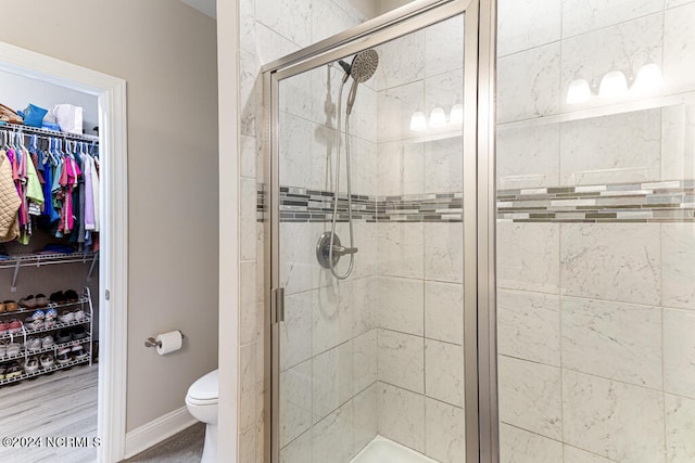 bathroom featuring a shower with door, hardwood / wood-style floors, and toilet