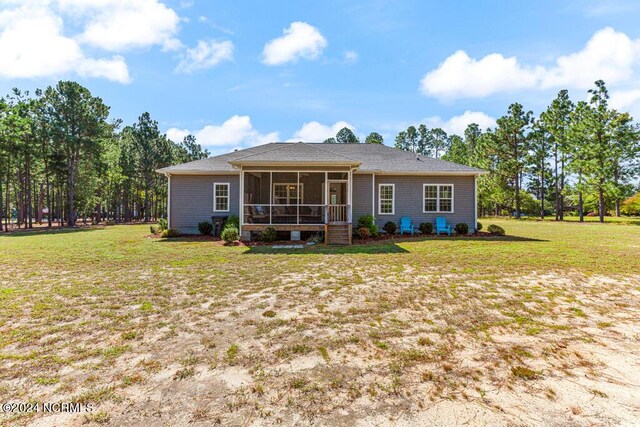 rear view of house featuring a sunroom and a lawn