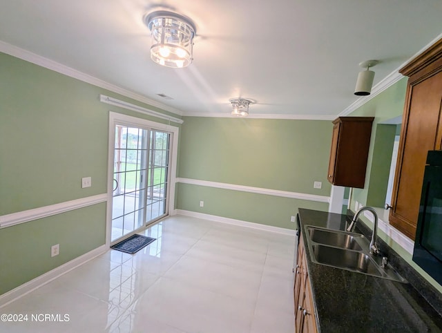 kitchen with dark stone counters, ornamental molding, and sink