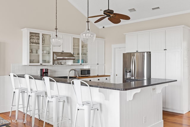 kitchen with light hardwood / wood-style floors, white cabinetry, a kitchen bar, stainless steel appliances, and ceiling fan