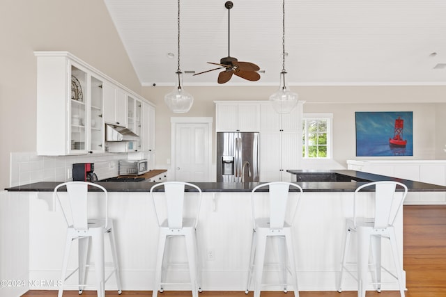 kitchen featuring stainless steel appliances, white cabinetry, kitchen peninsula, and a kitchen bar