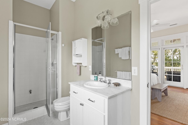 bathroom featuring ceiling fan, vanity, a shower with shower door, hardwood / wood-style flooring, and toilet