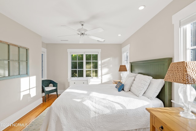 bedroom with multiple windows, ceiling fan, and hardwood / wood-style flooring