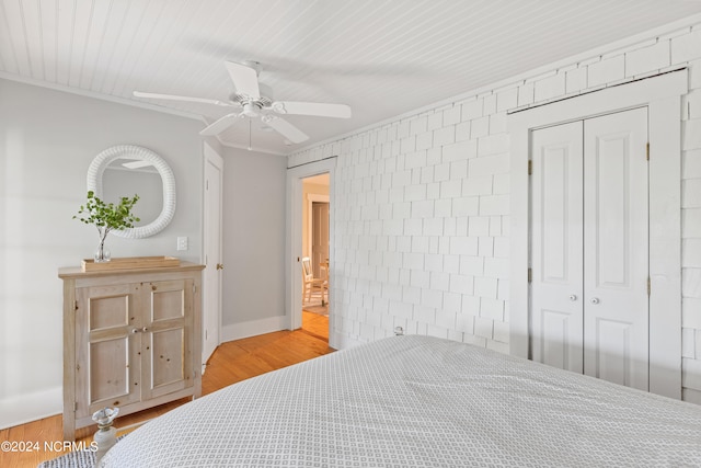 bedroom featuring brick wall, hardwood / wood-style floors, ceiling fan, and a closet