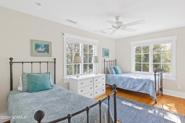 bedroom with wood-type flooring, multiple windows, and ceiling fan