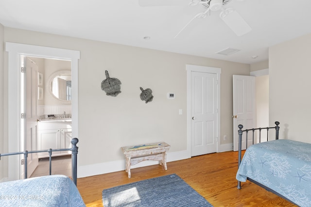 bedroom featuring light wood-type flooring, sink, ceiling fan, and ensuite bathroom