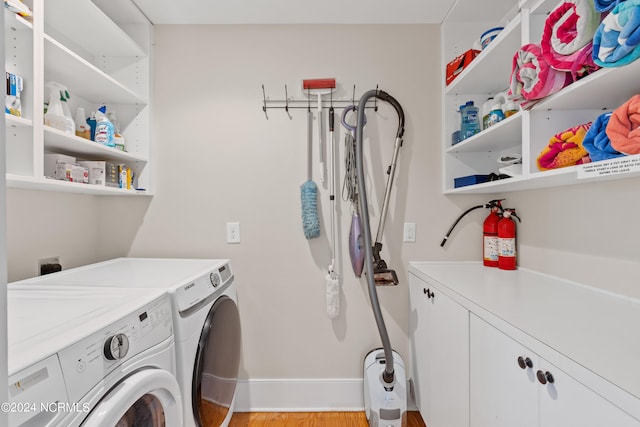 laundry room with separate washer and dryer, light hardwood / wood-style flooring, and cabinets