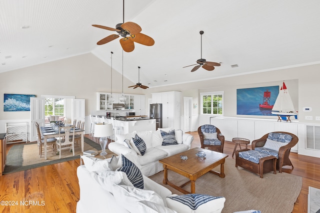 living room featuring high vaulted ceiling, light hardwood / wood-style floors, ceiling fan, and a wealth of natural light