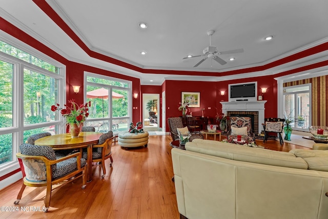 living room featuring plenty of natural light, crown molding, ceiling fan, and a brick fireplace
