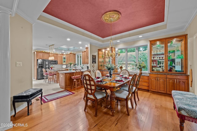 dining room with a tray ceiling, a chandelier, light wood finished floors, and ornamental molding