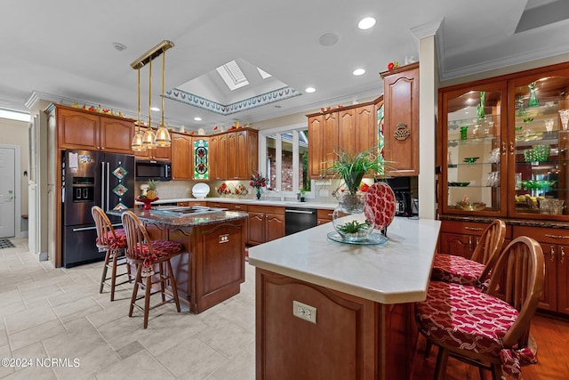 kitchen with brown cabinets, refrigerator with ice dispenser, a skylight, a breakfast bar area, and decorative backsplash