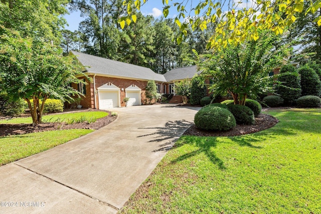 single story home featuring driveway, brick siding, a garage, and a front lawn