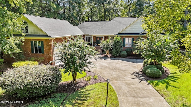 view of front of property featuring brick siding, a shingled roof, and a front lawn