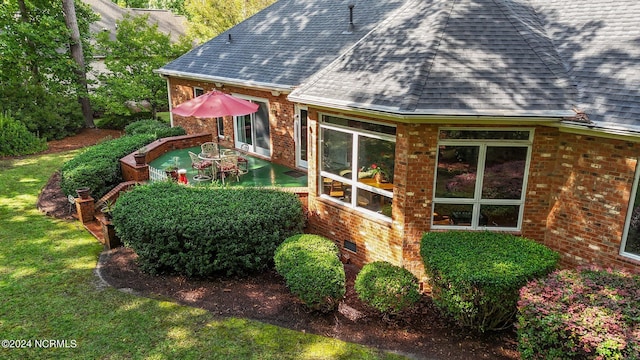 view of home's exterior with a lawn, brick siding, and roof with shingles