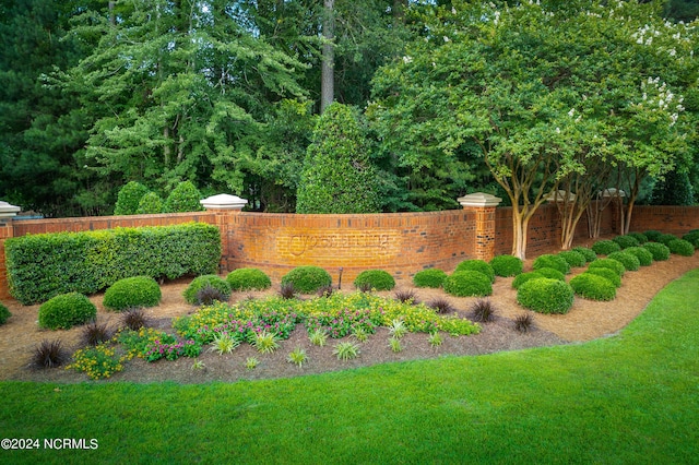 community / neighborhood sign featuring fence and a lawn