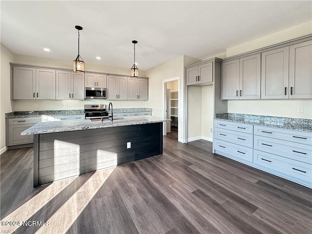 kitchen with pendant lighting, gray cabinets, stainless steel appliances, light stone countertops, and dark hardwood / wood-style flooring