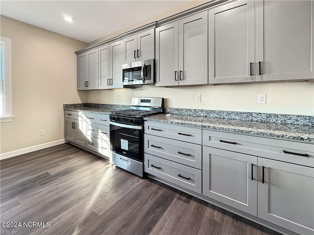 kitchen featuring gray cabinetry, dark hardwood / wood-style floors, stainless steel appliances, and light stone counters