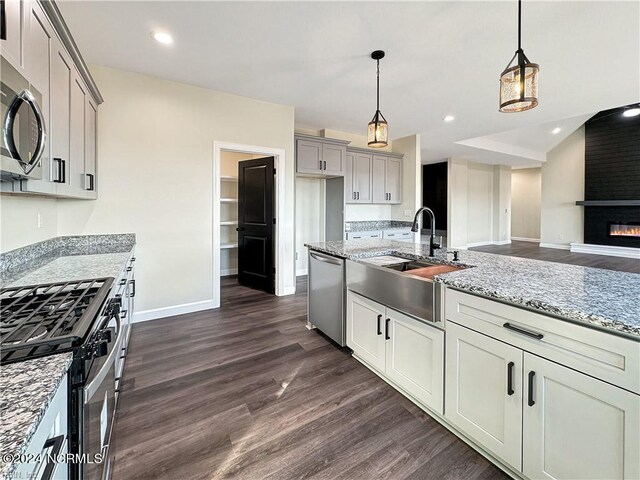 kitchen with pendant lighting, dark hardwood / wood-style floors, sink, a fireplace, and stainless steel appliances