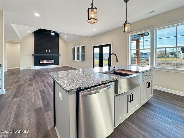 kitchen featuring vaulted ceiling, white cabinetry, hanging light fixtures, a fireplace, and stainless steel dishwasher