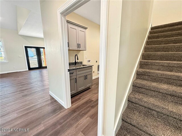 stairway with wet bar and hardwood / wood-style floors