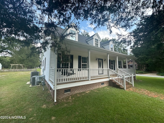 view of front of home featuring cooling unit, covered porch, and a front yard