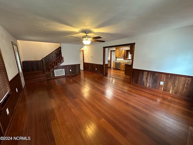 interior space featuring wooden walls, dark hardwood / wood-style flooring, and ceiling fan