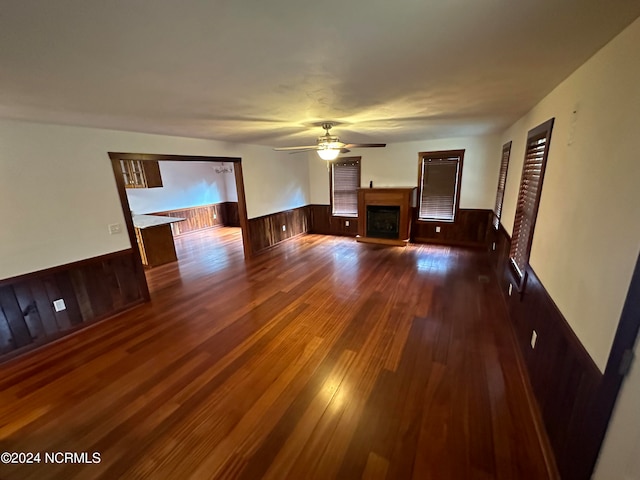 unfurnished room with ceiling fan, wooden walls, and dark hardwood / wood-style flooring