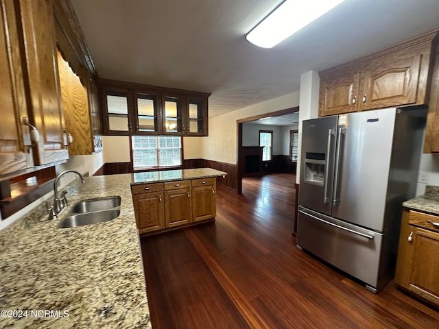 kitchen featuring kitchen peninsula, light stone countertops, stainless steel refrigerator with ice dispenser, dark hardwood / wood-style floors, and sink